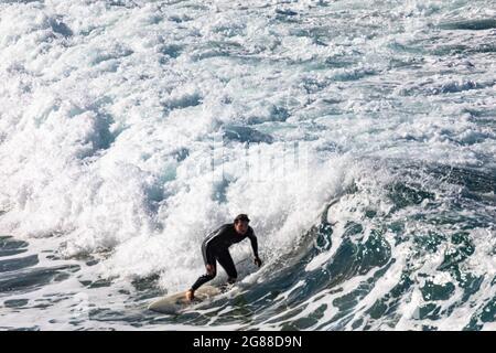 Australien en combinaison surfant sur les vagues à bord de mer à Avalon Beach Sydney, un jour hiverne, Australie Banque D'Images