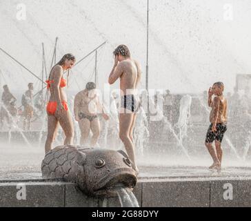 Les visiteurs du parc se refroidissent dans la fontaine d'eau, en été pendant la vague de chaleur, Parc de Saint-Pétersbourg 300 ann., Russie Banque D'Images