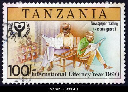 TANZANIE - VERS 1991 : timbre imprimé en Tanzanie consacré à l'année internationale de l'alphabétisation, lecture de journaux, vers 1991 Banque D'Images