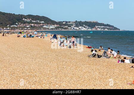 Les familles profitent du soleil sur une plage de galets à Hythe, dans le Kent. Banque D'Images