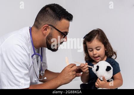 Médecin pédiatrique examinant la gorge d'une fille de 3 ans Banque D'Images