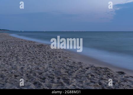 Vagues de mer magnifiquement floues au coucher du soleil après s'être écrasée contre le bord de mer Banque D'Images