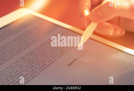 Concept de signature électronique. Une femme signe un contrat de distance avec un stylo numérique sur la tablette Banque D'Images