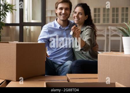 Le couple de collage s'assoit sur le canapé en tenant les clés pour célébrer le jour de déplacement Banque D'Images