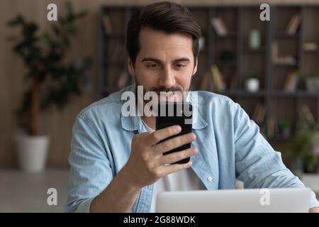 Jeune homme d'affaires souriant utilisant un smartphone au bureau. Banque D'Images