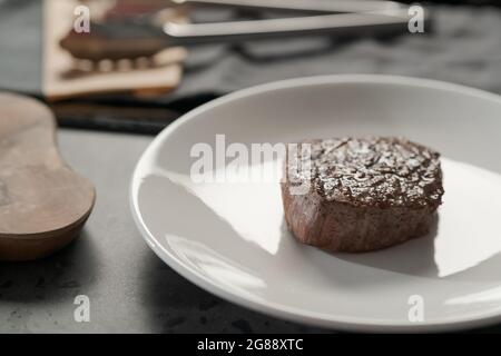 Steak de bœuf entier sur une assiette blanche, peu profonde Banque D'Images