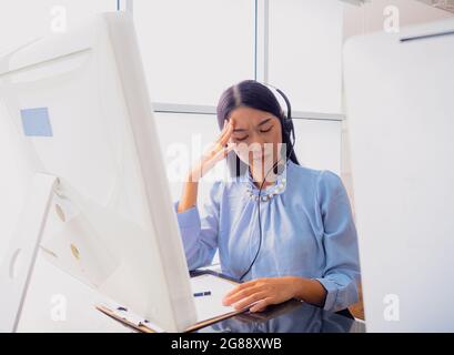 Une femme d'affaires faisant un massage du cou pour soulager la fatigue après avoir terminé une réunion en ligne avec des collègues tout en travaillant à la maison. Banque D'Images