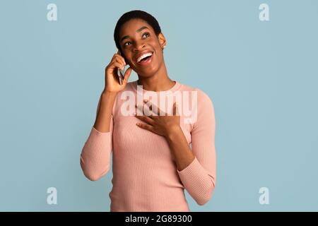 Appel mobile. Portrait d'une femme afro-américaine heureuse parlant au téléphone portable Banque D'Images