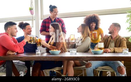 Joyeux amis multiraciaux amusant de toaster la bière à l'happy hour au pub - concept d'amitié avec les gens heureux ayant le plaisir ensemble ils parlent dans le Banque D'Images