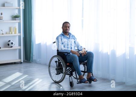 Dépression chez les patients handicapés. Portrait d'un homme noir paraplégique en fauteuil roulant ayant des problèmes psychologiques à la maison Banque D'Images