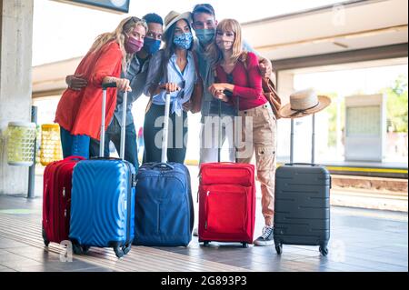 Groupe multiracial d'amis à la gare avec des bagages portant un masque de protection faire un selfie - Tourisme et de vacances concept pendant Covid19 pandem Banque D'Images