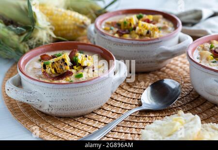 Vue rapprochée des crocks à soupe remplis de poulet et de chaudrée de maïs grillé, de bacon et de ciboulette. Banque D'Images