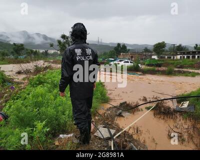 Pékin, Chine. 18 juillet 2021. Un policier vérifie une route ruinée par des inondations déclenchées par des pluies torrentielles dans le district de Mentorgou à Beijing, capitale de la Chine, le 18 juillet 2021. L'Observatoire météorologique de Beijing a émis dimanche matin un avertissement orange pour les pluies accumulées dans certaines zones de la capitale ayant dépassé 150 mm. Credit: Xinhua/Alay Live News Banque D'Images