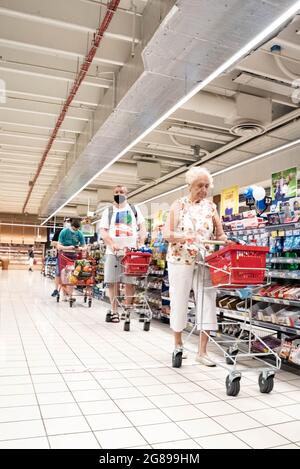 Varsovie, Pologne - 27 juin 2021 : personnes avec des paniers de shopping alignés pour les groats au magasin. Faire du shopping dans un supermarché pendant l'épidémie de COVID-19. Banque D'Images