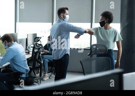 Homme d'affaires et femme d'affaires avec masque médical au bureau. Salutations à Covid-19 fois Banque D'Images