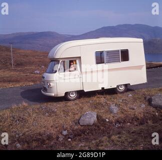 1970, historique, visite des Highlands écossais, une dame assise dans un campervan de Commer, un roadranger de 'Jennings' 2500 sur une route à flanc de colline sur l'île de Harris, Highlands, Écosse, Royaume-Uni. Le Roadranger était un camping-car construit en autocar, la production a commencé en 1968, développé à partir du Commer FC. Fabricant britannique de véhicules commerciaux, Commer a commencé en 1905 sous le nom de Commerical Cars Ltd. Dans l'histoire en damier qui est la fabrication automobile britannique, Commer a été introduit par Humber en 1926, Puis, en 1931, devient un sous-sidaire du groupe Rootes, puis Chrysler en 1967, puis Renault en 1979. Banque D'Images