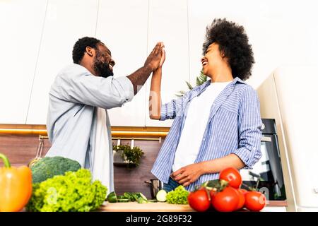 Belle cuisine afro-américaine couple à la maison - beau et gai noir couple préparant le dîner ensemble dans la cuisine Banque D'Images
