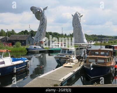 Vue sur les Kelpies de l'autre côté de la marina de Kelpie dans Helix Park avec des bateaux amarrés à la jetée et les chevaux se dirige en arrière-plan. Banque D'Images