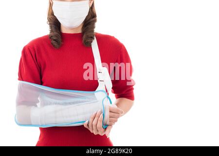 Belle femme asiatique avec bras cassé et bandage portant masque chirurgical d'hygiène de protection debout isolé sur fond blanc avec visage smiley. Po Banque D'Images