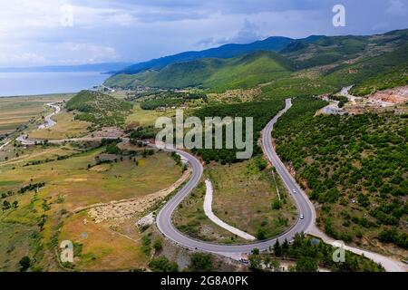 Vue d'en haut sur le lac Ohrid, le village de pêcheurs Lin et la route panoramique sinueuse de montagne, prise par drone. Albanie, Europe Banque D'Images