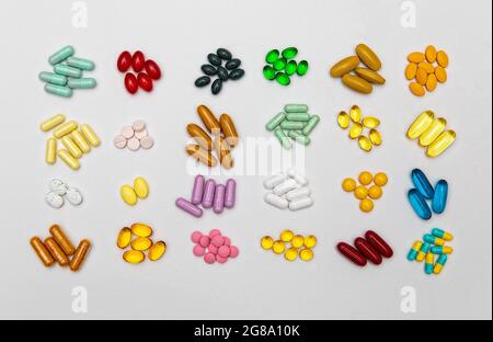 Groupe de comprimés pharmaceutiques assortis, comprimés et capsules colorés de différentes tailles sur fond de papier blanc. Banque D'Images