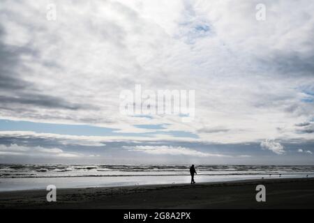 Moody image de randonneurs silhouetted sur la plage à côté de l'océan Pacifique, Pacific Beach, Washington State USA. Banque D'Images