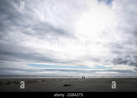 Moody image d'un couple de marche silhouetted sur la plage à côté de l'océan Pacifique, Pacific Beach, Washington State USA. Banque D'Images