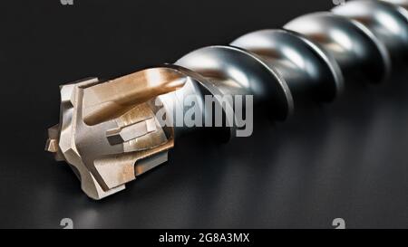 Foret hélicoïdal avec fraises en carbure sur pointe, dans une vie artistique sur fond noir. Un outil de coupe à vis en métal brillant aux détails magnifiques. Banque D'Images