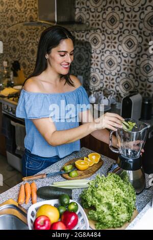 Femme latine faisant du smoothie vert ou du jus de Detox dans la cuisine à la maison dans le concept de saine alimentation au Mexique Banque D'Images