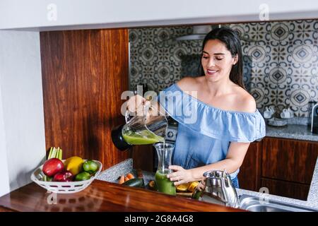 Femme latine faisant du smoothie vert ou du jus de Detox dans la cuisine à la maison dans le concept de saine alimentation au Mexique Banque D'Images