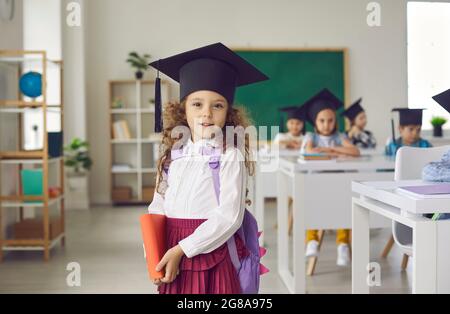 Portrait d'une jeune fille d'école élémentaire souriante dans le chapeau de graduation Banque D'Images