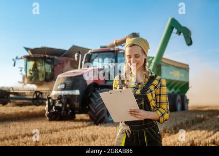 Agriculteur sur le champ de grain avec le tracteur et la moissonneuse-batteuse en arrière-plan Banque D'Images