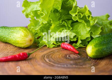 Aliments sains frais : salade verte, concombres et piments rouges sur une planche à découper. Concept d'alimentation saine. Végétarisme. Banque D'Images