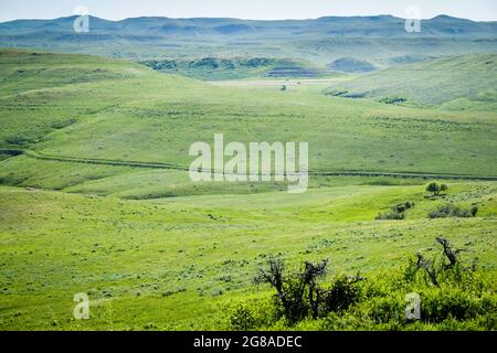 Les véhicules parcourent l'Interstate 90 près de Story, Wyoming, avec des ornières de wagon de l'ancien Bozeman Trail clairement visibles sur le flanc de la colline, au milieu de la distraction. Banque D'Images