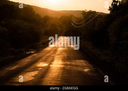 Coucher de soleil sur une route d'asphalte rurale près de Cooperstown, New York, États-Unis. Banque D'Images