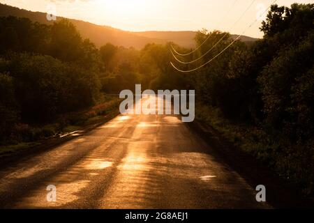 Coucher de soleil sur une route d'asphalte rurale près de Cooperstown, New York, États-Unis. Banque D'Images