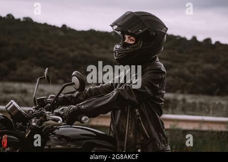 Portrait d'une automobiliste confiante dans un casque de moto. Jeune motard qui regarde seul l'extérieur sur l'autoroute. Prêt pour le voyage. Courses de café Banque D'Images