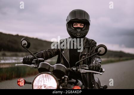 Portrait d'une automobiliste confiante dans un casque de moto. Jeune motard qui regarde seul l'extérieur sur l'autoroute. Prêt pour le voyage. Courses de café Banque D'Images