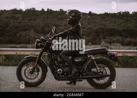 Portrait d'une automobiliste confiante dans un casque de moto. Jeune motard qui regarde seul l'extérieur sur l'autoroute. Prêt pour le voyage. Courses de café Banque D'Images