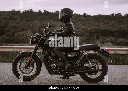 Portrait d'une automobiliste confiante dans un casque de moto. Jeune motard qui regarde seul l'extérieur sur l'autoroute. Prêt pour le voyage. Courses de café Banque D'Images