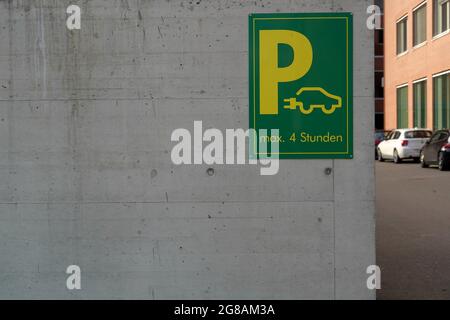 Panneau indiquant la place de stationnement avec les postes de charge pour les voitures électriques en vert et jaune. Banque D'Images