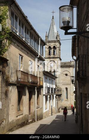 Camino de Santiago (chemin de Saint James). Les pèlerins se promo dans le centre-ville de Sarria, en Galice, en Espagne. L'église de Saint Marina (Iglesia de Santa Mariña de Sarria) achevée en 1885 est vue en arrière-plan. Sarria est la ville la plus peuplée sur la route française du Camino de Santiago en Galice. Banque D'Images