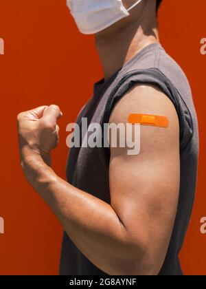 Vaccins, pansement sur le concept de bras de personnes vaccinées. Le bandage adhésif de couleur orange sur le bras de l'homme fort qui se fend la main et montrant mu Banque D'Images