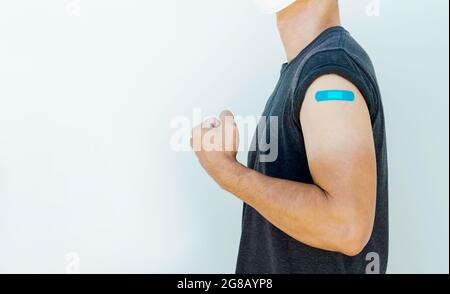 Vaccins, pansement de bandage et concept de personnes vaccinées. Bandage bleu sur le bras de l'homme fort qui se fend la main et montrant le muscle après le traitement de vaccination Banque D'Images