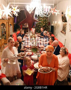 18 juillet 2021, Saxe, Hayna/Schkeuditz: Martina Sawatzke se tient avec sa petite-fille de huit ans, Alisia et sa fille Eva (r-l) avec le repas festif dans la salle de Noël décorée. Au milieu de l'été, Dietmar Sawatzke, 70 ans, et sa femme Martina, qui a le même âge, sont en train de faire le repas de Noël qui a été annulé en décembre en raison de la pandémie de Corona lors d'un grand rassemblement avec des amis et de la famille. Dans la grande salle de fête, où un arbre de Noël décoré, des étoiles brillantes sur le plafond et des chants de Noël fournissent l'atmosphère de Noël, il y a ensuite rôti d Banque D'Images