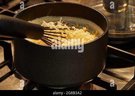 Fromage dans une casserole sur cuisinière à gaz pour faire de la sauce. Banque D'Images