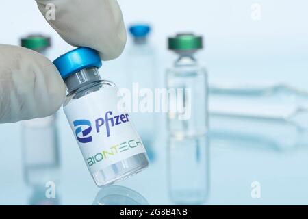 Flacon en verre avec logo Pfizer et BioNTech dans la main du médecin, société pharmaceutique multinationale américaine. 18 janvier 2021, Barnaul, Russie. Banque D'Images