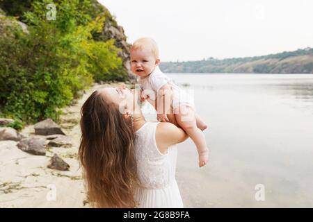 Mère avec bébé à l'extérieur près de la rivière. Le concept d'une famille heureuse Banque D'Images