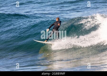 Australien en combinaison surfant sur les vagues à bord de mer à Avalon Beach Sydney, un jour hiverne, Australie Banque D'Images