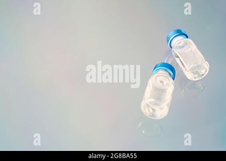 Flacons en verre avec liquide vaccinal sur fond bleu. Le concept de la médecine, de la vaccination et de l'injection. Banque D'Images